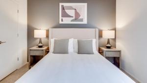 una camera da letto con un grande letto bianco con due lampade di Landing - Modern Apartment with Amazing Amenities (ID7851X76) a Buffalo Grove