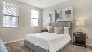 een slaapkamer met een bed met witte lakens en 2 lampen bij Landing - Modern Apartment with Amazing Amenities (ID1192X099) in Kissimmee
