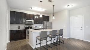 een keuken met een keukeneiland met stoelen erin bij Landing - Modern Apartment with Amazing Amenities (ID1192X099) in Kissimmee