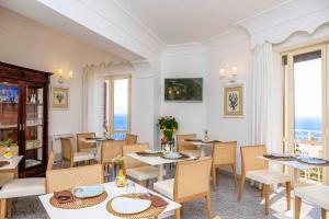 uma sala de jantar com mesas e cadeiras e o oceano em Residenza Al Pesce D'Oro em Amalfi