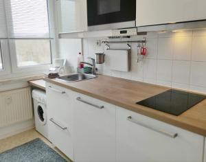 una cocina con armarios blancos y fregadero en Apartment E - feel good, en Leipzig