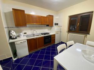 cocina con armarios de madera y suelo de baldosa azul en Gravina House, en Portici