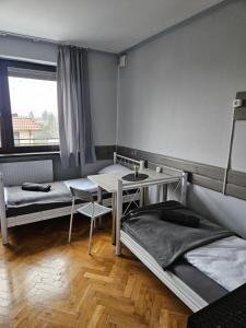 Zimmer mit 2 Betten, einem Tisch und einem Fenster in der Unterkunft Pokoje na Wilkońskich, Swarzędz in Swarzędz