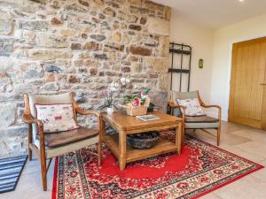 a living room with a table and chairs and a stone wall at Hill Brook Barn in Clitheroe