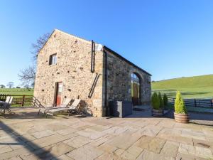 a stone building with two benches on a patio at Hill Brook Barn in Clitheroe