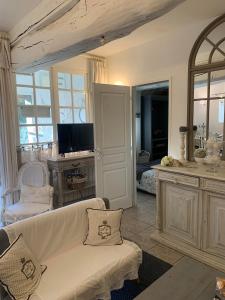 ein Wohnzimmer mit einem weißen Sofa und einem TV in der Unterkunft Bleu D'Orage in Vimoutiers