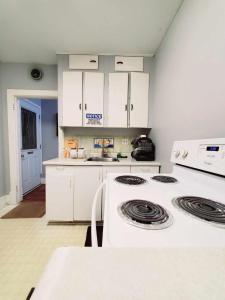 - une cuisine avec des placards blancs et une cuisinière dans l'établissement Merj's Guest House in Wolesly, à Winnipeg