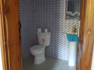 a bathroom with a white toilet and a sink at La maison Yaka in Boukot Ouolof