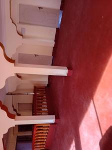 une cage d'escalier dans une pièce avec un mur rouge dans l'établissement Maison d'Hôtes Agdal Telouet, à Tiguidert