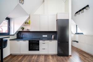 a kitchen with white cabinets and a black refrigerator at Cozy Central Attic SELF Check In in Vilnius