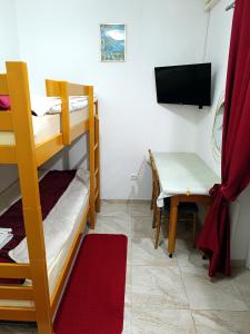 Zimmer mit Etagenbetten, einem Tisch und einem TV in der Unterkunft Java apartments - S & J in Dobrota