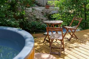 two chairs and a table on a wooden deck at Les Jardins du Nideck in Oberhaslach