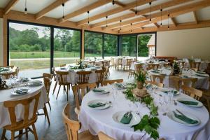 een feestzaal met witte tafels en stoelen en grote ramen bij Les Jardins du Nideck in Oberhaslach