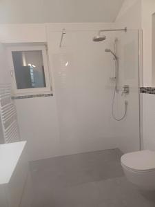 uma casa de banho branca com um chuveiro e um WC. em Ferienwohnung Maria & Luis em Kolsass