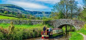 two people standing on a boat in a canal under a bridge at Queen Victoria House By MGroupSA in Tredegar