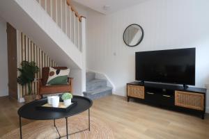 een woonkamer met een flatscreen-tv en een tafel bij Queen Victoria House By MGroupSA in Tredegar