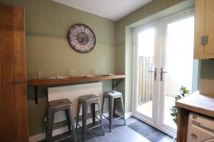 uma cozinha com um bar com bancos e um relógio na parede em Queen Victoria House By MGroupSA em Tredegar