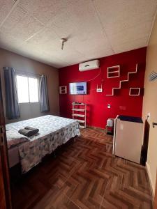 um quarto com uma cama e uma parede vermelha em Residência Shalom em Presidente Figueiredo