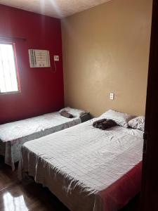 2 Betten in einem Zimmer mit roten Wänden in der Unterkunft Residência Shalom in Presidente Figueiredo