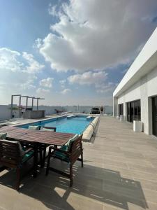 eine Terrasse mit einem Tisch und Stühlen neben einem Pool in der Unterkunft Al Saleh Chalet in Al Sharqiyah