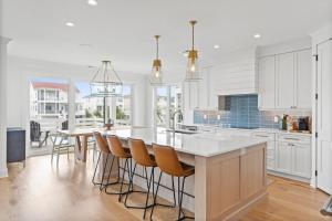 a kitchen with white cabinets and a table with chairs at 25 Cumberland - Canal front with dock, Custom home finishes in Ocean Isle Beach