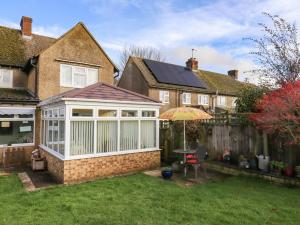 a house with a conservatory with a table and an umbrella at Molly's Bit in Chipping Norton