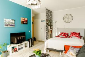 1 dormitorio con 1 cama con almohadas rojas y TV en Studio: Alex’s secret!, en Pori