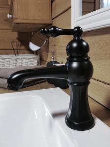 a black faucet sitting on top of a sink at Trainiškio pirkia in Ginučiai