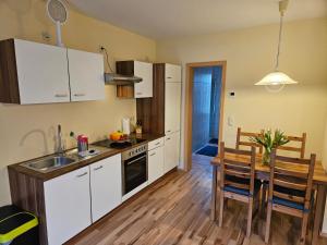 a kitchen with white cabinets and a wooden table with a dining room at Ferienwohnung Ostsee und Strand in Ribnitz-Damgarten