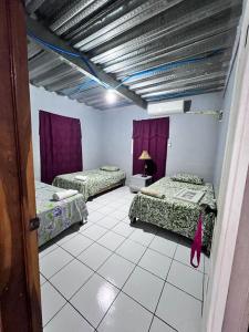 três camas num quarto com cortinas roxas em Hotel Pacific Surf AC Room Best in Tunco Beach em Tamanique