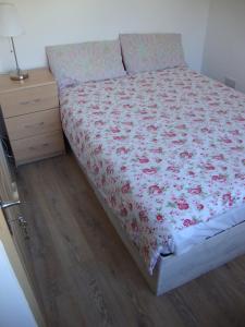 a bedroom with a bed with a floral bedspread and a night stand at Unique World War II history attached to this dwelling in Dublin