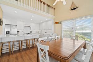 a kitchen with a wooden table and white chairs at A Coconut Hut Brunswick Vacation Rentals in Oak Island
