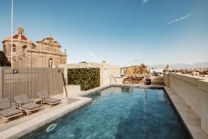 una piscina sul tetto di un edificio con sedie di Palazzo Castagna Boutique Hotel a Hal Ghaxiak