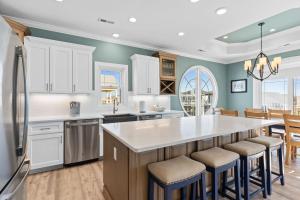 a kitchen with white cabinets and a large island with bar stools at All the Views Ocean Isle Beach, heated private pool, close to beach in Ocean Isle Beach