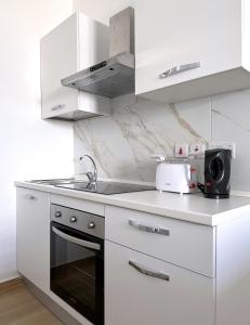 a white kitchen with a sink and a microwave at Miami Apartments in St. Julianʼs