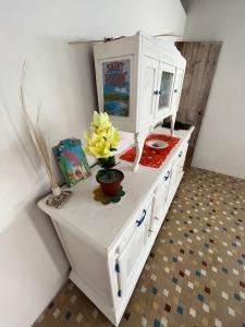 a white cabinet with a vase with flowers on it at Case Louis et spa in Saint-Pierre