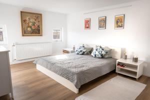 ein weißes Schlafzimmer mit einem Bett und Gemälden an der Wand in der Unterkunft Moderne Wohnung, citynah, mit Ausblick über die Stadt in Hannover