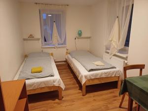 two beds in a room with two windows at Hostinec Klopoty in Říčky