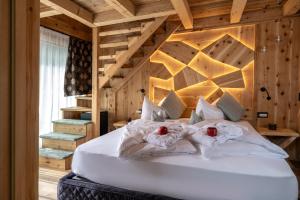 a bedroom with a large white bed with wooden walls at Alpine Residence Villa Adler in San Vigilio Di Marebbe