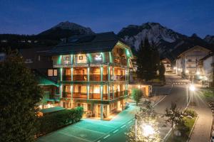 a large building with mountains in the background at night at Alpine Residence Villa Adler in San Vigilio Di Marebbe