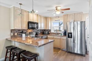 een keuken met houten kasten en een roestvrijstalen koelkast bij Beach D-ehs Brunswick Vacation Rentals in Ocean Isle Beach