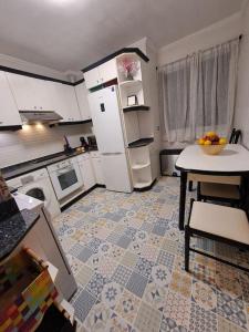 eine Küche mit einem Tisch und einem weißen Kühlschrank in der Unterkunft Bilbao, a un paso. in Bilbao