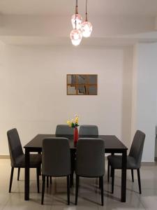 comedor con mesa negra y sillas en DESARU SERENITA Homestay NETFLIX WIFI, en Bandar Penawar