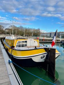 un barco blanco y amarillo atracado en un muelle en UNE PENICHE DANS LE BASSIN À FLOT DU VIEUX PORT, en La Rochelle