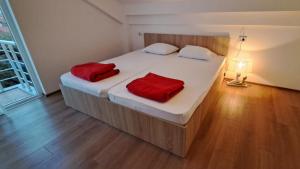 a bedroom with a bed with two red pillows on it at Libertas Apartments in Bitola
