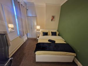 a bedroom with two beds and a green wall at Primos Executive - 2 Bedroom House in Wallsend in Old Walker