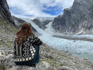 a woman sitting on a mountain looking at a glacier at Tungestølen in Veitastrond