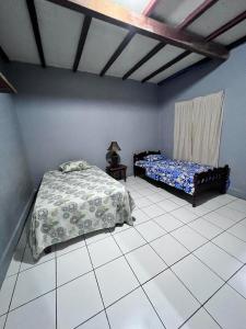 a bedroom with two beds and a tiled floor at Hotel Pacific Surf Room with AC best place in Tunco in Tamanique