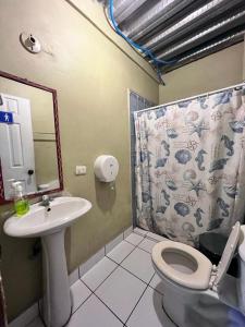 uma casa de banho com um lavatório, um WC e um espelho. em Hotel Pacific Surf Room with AC best place in Tunco em Tamanique