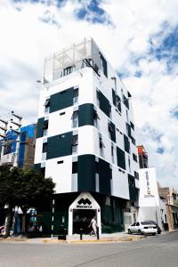 a white and black building with a man standing in front of it at Zentra Hotel in Chiclayo
